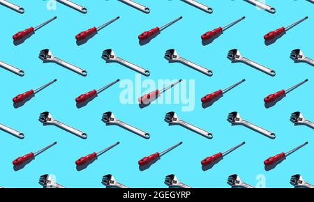 Screwdriver and wrench, pattern on a blue background. Construction tools, repairs. Background for the design. Stock Photo