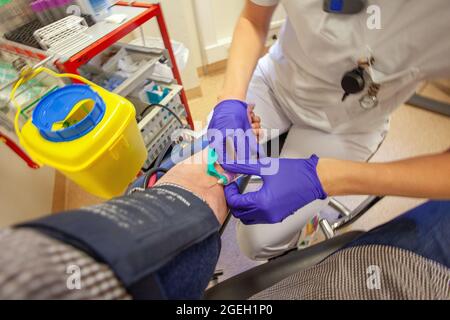 Blood test being performed on a middle aged man's arm by a Practice Nurse Stock Photo