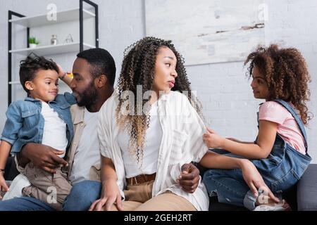 positive african american family talking while sitting on sofa at home Stock Photo