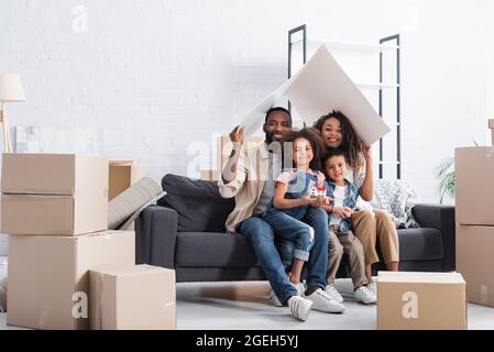 african american couple sitting under paper roof on sofa Stock Photo