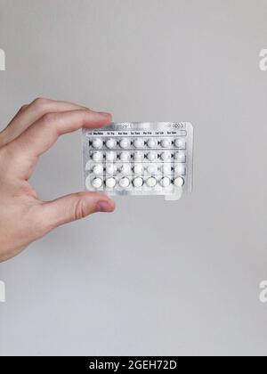A woman holding birth control pills on white background