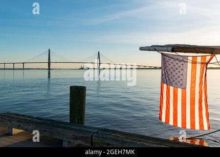 The US flag hanging from the bough of a boat in the Cooper River in front of the Arthur Ravenel Jnr bridge in Charleston, South Carolina, USA Stock Photo