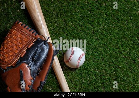 Baseball and wood bat with mitt on grass field overhead view Stock Photo