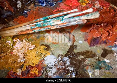 Painter's brushes and colorful almost abstract pallet full of paint Stock Photo