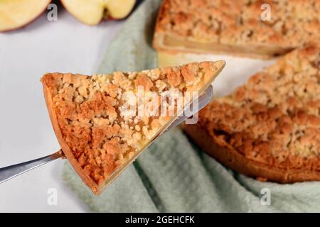 Slice of traditional European apple pie with topping crumbles called 'Streusel' on cake server Stock Photo