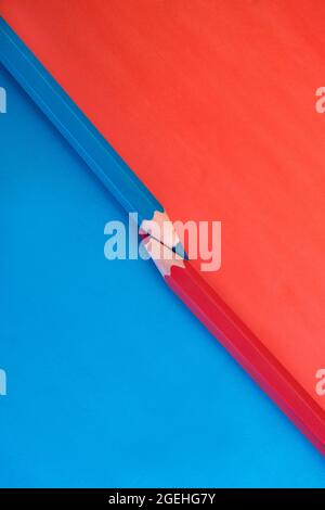 Macro shot of two vibrant pink and blue colored pencils with the tips touching on a matching background with opposite colors. Top down view flat lay Stock Photo