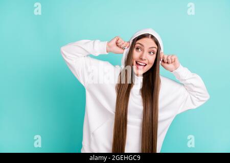 Photo of adorable impressed young lady wear white sweatshirt smiling looking empty space isolated turquioise color background Stock Photo