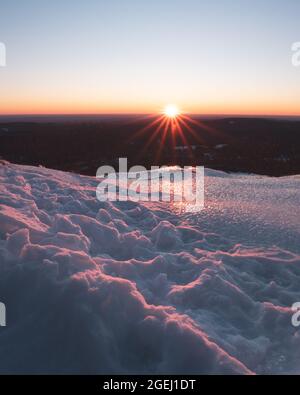 Sunrise seen from the summit of Mount Watatic in Ashburnham Massachusetts on a cold snowy winter morning. The rising sun is forming a sun star. Stock Photo