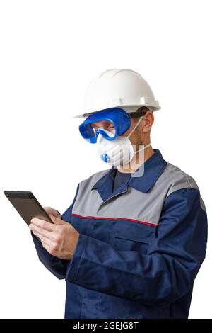 Portrait of a man in a work clothes, white construction helmet, respirator and protective glasses with tablet in hands. Isolated on white. Stock Photo