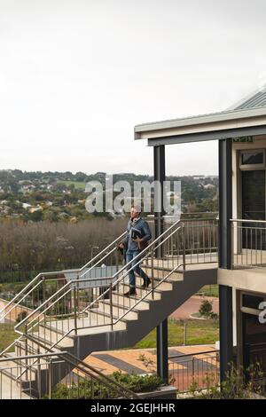 Serious caucasian male business creative walking downstairs holding notebooks Stock Photo