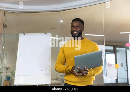 Smiling african american male business creative holding laptop, making presentation Stock Photo