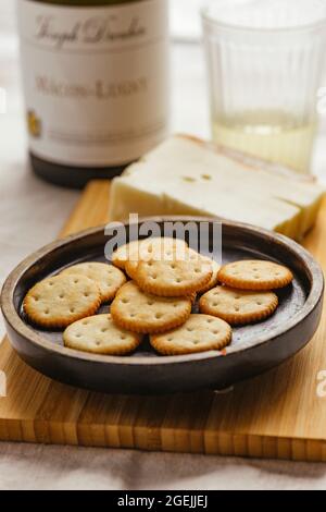 Cheese Biscuits or Crackers on a Plate with Cheese and a Glass of White Wine Stock Photo