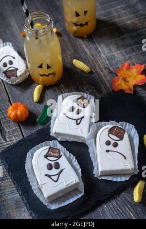 Homemade baked halloween party. Funny cookies in white chocolate glaze ghost on a wooden table. Stock Photo