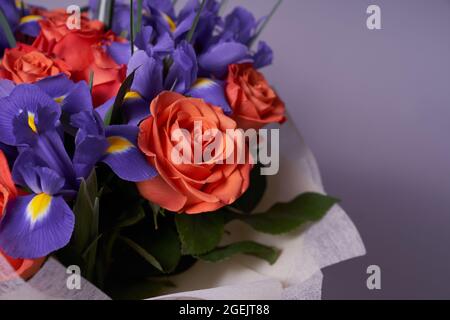 A colorful bouquet of flowers made of orange roses and purple irises. On a light background. A place to copy. The concept of the holiday. High quality photo Stock Photo