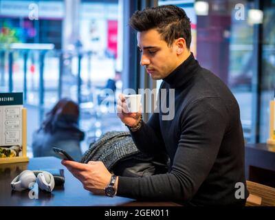 Attractive Man Drinking Coffee and Using Smartphone Stock Photo
