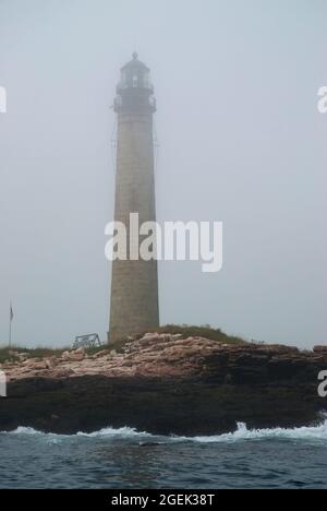 Fog surrounds Petit Manan lighthouse, the second tallest lighthouse tower in Maine. It is part of the Coastal Islands Wildlife Refuge for birds. Stock Photo