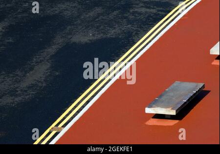 Overhead view of double yellow 'no parking' lines on a new road and a concrete bench in the Brunswick area of Manchester, England, United Kingdom. Stock Photo