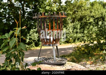 Old rusty metal fire brazier with old burned charcoal in forest Stock Photo