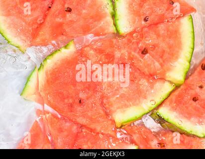 Melon close-up in liquid with bubbles. Slicec of red ripe melon in water. Close-up fresh slices of red melon on white background. Stock Photo