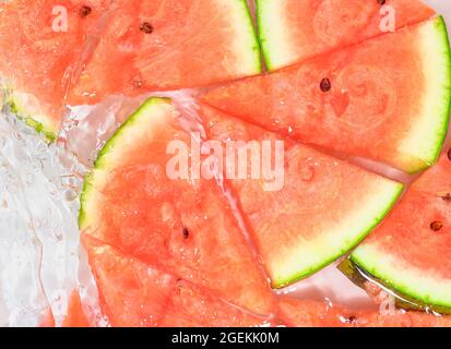 Slices of melon in water on white background. Melon close-up in liquid with bubbles. Slices of red ripe melon in water. Macro image of fruits in water Stock Photo
