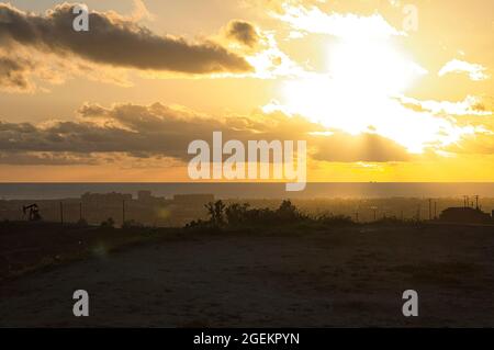 sunlight streaming through clouds at sunset over grassy beach in late afternoon Stock Photo