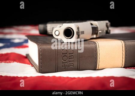 A gun and holy bible rests atop an American flag representing God, guns and freedom of religion. Stock Photo