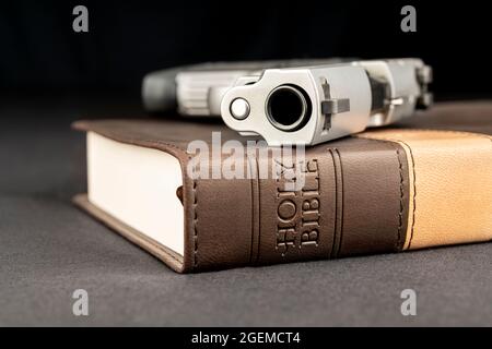 A gun rests atop a holy bible, representing God, guns and freedom of religion. Stock Photo