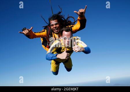 July 12, 2009. Porto Belo, Santa Catarina, Brazil. A dreadlocked instructor and a student jump tandem parachute in bliss. Stock Photo