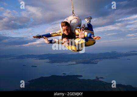 February 1, 2008. Porto Belo, Santa Catarina, Brazil. An instructor and a student jump tandem parachute in complete happiness. Sunset and the island o Stock Photo