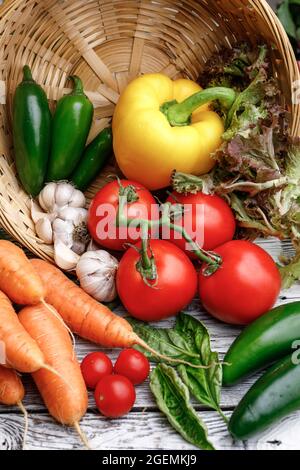 Assorted vegetables and basil in a basket on a wooden table. Stock Photo