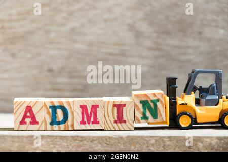 Toy forklift hold letter block N in word admin on wood background Stock Photo