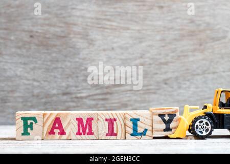 Toy bulldozer hold letter block y to complete word family on wood background Stock Photo