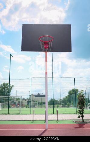Basketball backboard with a basket made of iron chains on a sunny day. Vertical view. Low angle view Stock Photo