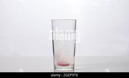 Effervescent tablet falls into a glass of water on a white background Stock Photo