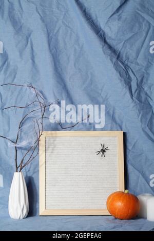 felt letter board with space for text with candle, pumpkin on crumpled blue textile material.halloween day composition.party greeting card. Stock Photo