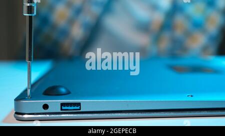 Unrecognizable man screwing bolts into laptop cover after repair Stock Photo