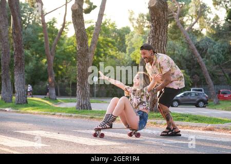 Young cool tattooed couple having fun skateboarding. Stock Photo