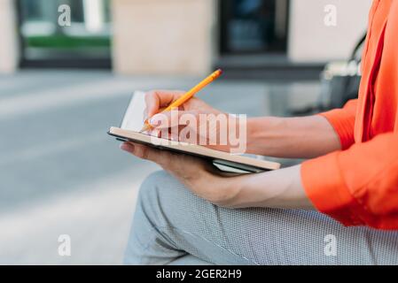 Person makes notes in a notebook with a pencil Stock Photo