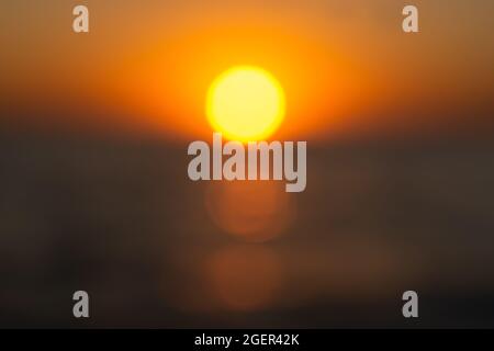 The summer sun is a blurry sunset background. Hot sultry background for summer design. Beautiful bokeh, brilliant sea, warm rays of sunset or dawn. Ab Stock Photo