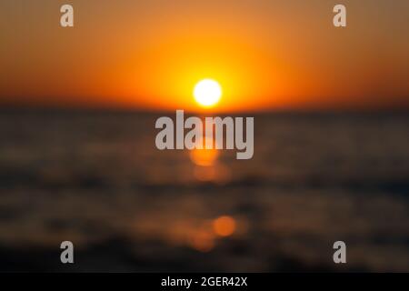 The summer sun is a blurry sunset background. Hot sultry background for summer design. Beautiful bokeh, brilliant sea, warm rays of sunset or dawn. Ab Stock Photo