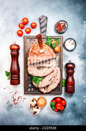 Traditional Meatloaf with mashrooms, baked pork beef minced meat on wooden cutting board on gray table. Top view, negative space Stock Photo