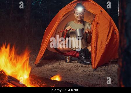 Tourist using camping tableware for getting tea out of pot Stock Photo