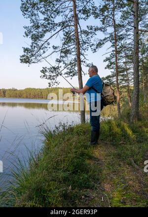 Fishing adventures, carp fishing. Fisherman on a lake shore with