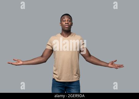 Dark-skinned young man not knowing what to do Stock Photo