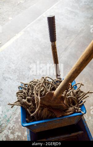 old mop with wooden handle and blue mop bucket Stock Photo