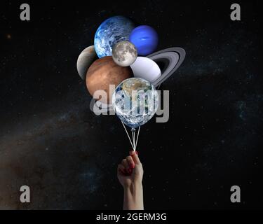 Hand with planets shaped balloons in solar system. Elements of this image furnished by NASA. Stock Photo