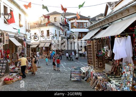 summer cityscape – street of ancient town with souvenir shops and tourists. Old historical architecture, Gjirokaster, Albania, Stock Photo