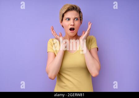 portrait of attractive lovable cute worried nervous , shocked short-haired caucasian woman having panic expression isolated over purple pastel color b Stock Photo