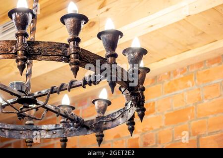 Old medieval metal chandelier in the ancient castle in gothic style with electrical lamps. Stock Photo