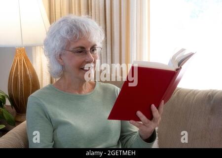 Happy smiling senior woman reading book at home. Concept: age, leisure and people Stock Photo